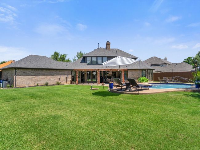 Rear view of property featuring brick siding, a patio, a chimney, and a shingled roof | Image 33