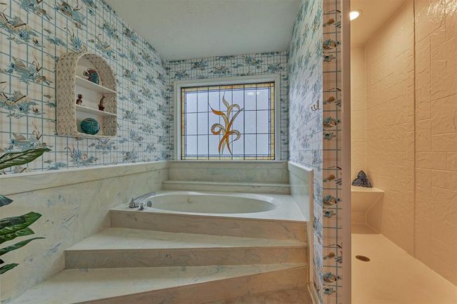 This bath features a large soaking tub and separate shower. Built-ins near the shower offer convenient storage for toiletries and towels. | Image 32