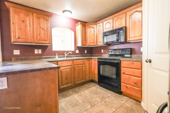 Kitchen featuring black appliances, light tile patterned floors, and dark countertops | Image 20