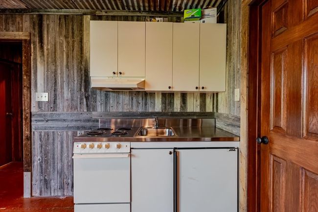 Kitchen featuring stainless steel counters, under cabinet range hood, a sink, and white fridge | Image 19