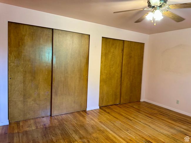 Unfurnished bedroom featuring two closets, wood finished floors, and a ceiling fan | Image 10