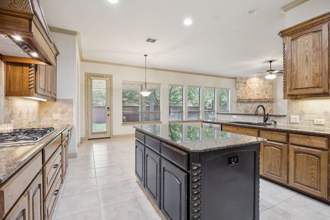 Kitchen featuring stainless steel appliances, a sink, custom exhaust hood, a kitchen island, and backsplash | Image 15