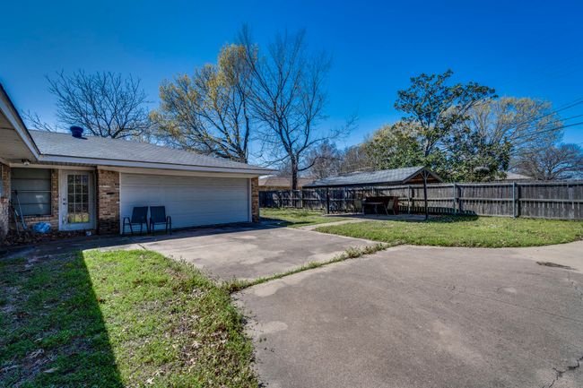 View of side of home with fence, concrete driveway, a garage, a lawn, and brick siding | Image 18
