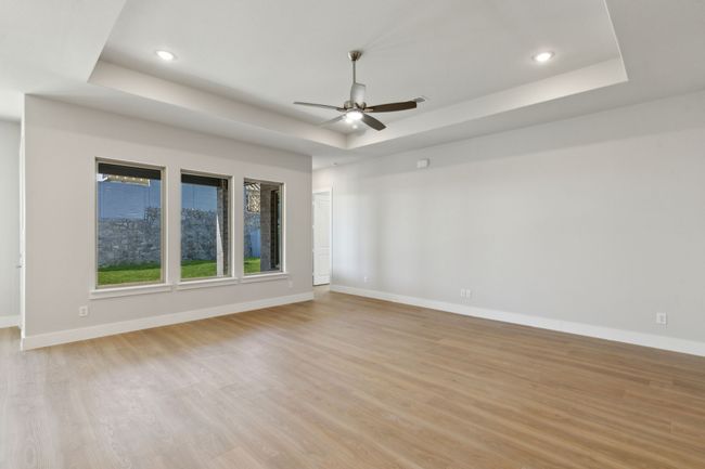 Empty room with a tray ceiling, ceiling fan, light wood-style flooring, and recessed lighting | Image 13