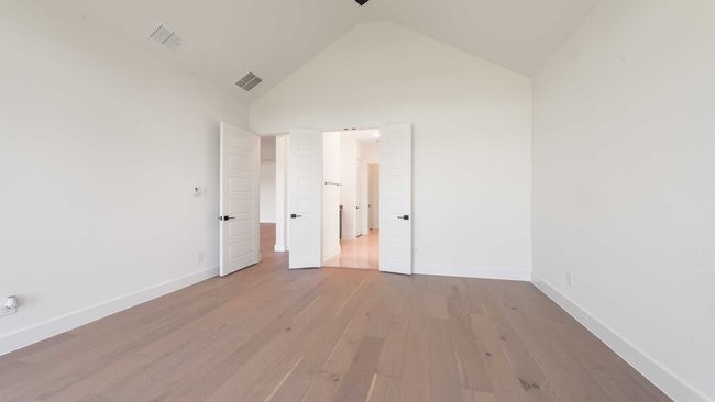 Unfurnished bedroom featuring baseboards, visible vents, wood finished floors, and vaulted ceiling | Image 16