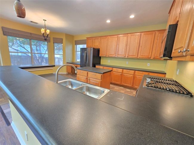Kitchen featuring dark countertops, appliances with stainless steel finishes, recessed lighting, a chandelier, and decorative light fixtures | Image 13