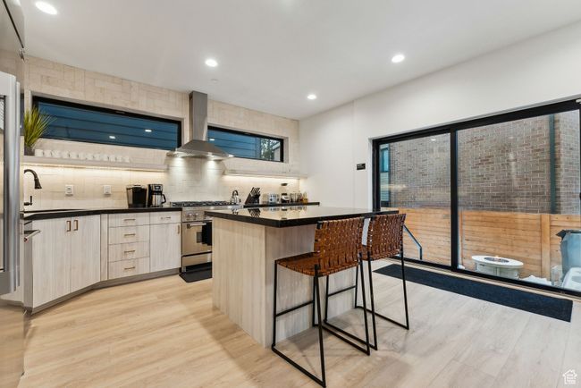Kitchen with a center island, extractor fan, sink, high end stainless steel range oven, and light hardwood / wood-style flooring | Image 8
