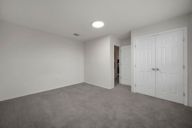 Unfurnished bedroom featuring a closet, baseboards, dark colored carpet, and visible vents | Image 16