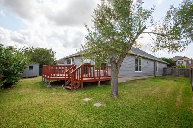 Rear view of house featuring a storage unit, a lawn, and a wooden deck | Image 29