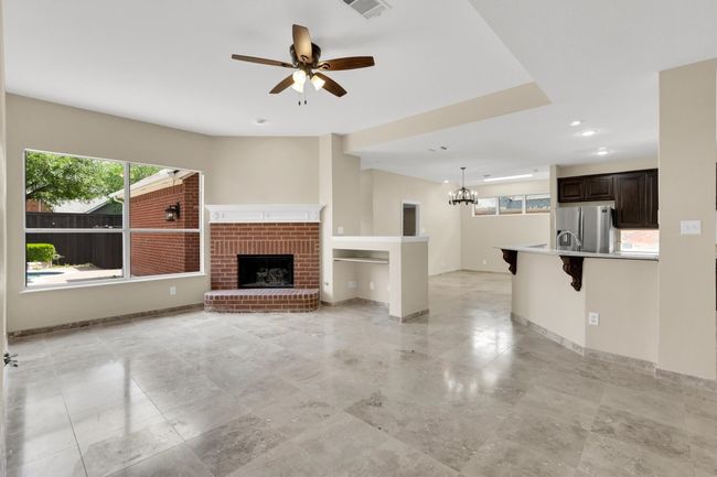 Unfurnished living room with recessed lighting, visible vents, baseboards, a fireplace, and ceiling fan with notable chandelier | Image 11
