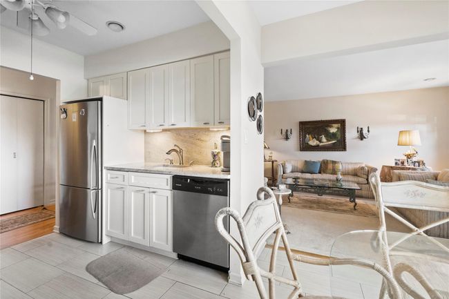 Kitchen featuring appliances with stainless steel finishes, open floor plan, white cabinetry, and light stone countertops | Image 13