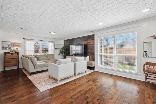 Living area featuring wood-type flooring, an ornate ceiling, wooden walls, and ornamental molding | Image 6