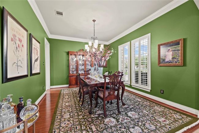 Formal Dining Room with polished wooden floor, crown molding, and wooden shutters create an ideal atmosphere for luxurious dinners and relaxed family gatherings. | Image 4