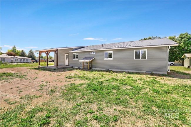 Rear view of house featuring a metal roof, a lawn, and a patio area | Image 29