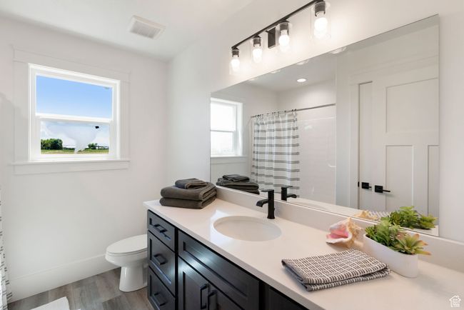Full bathroom featuring toilet, vanity, wood finished floors, a shower with shower curtain, and baseboards | Image 14