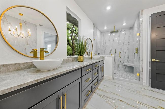 Bathroom featuring tiled shower, vanity with extensive cabinet space, double sink, tile floors, and an inviting chandelier | Image 27