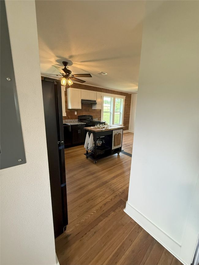 Kitchen featuring freestanding refrigerator, white cabinets, dark wood-style floors, a ceiling fan, and backsplash | Image 6