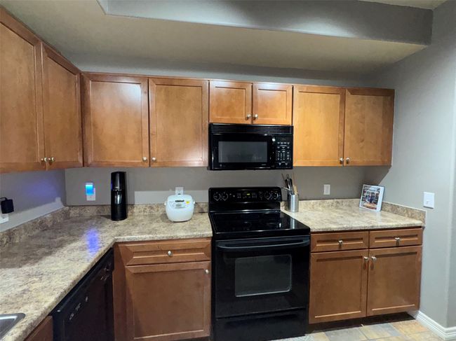 Kitchen with light stone counters and black appliances | Image 14