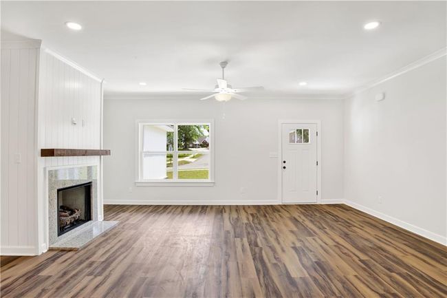 Unfurnished living room with a high end fireplace, baseboards, ornamental molding, and wood finished floors | Image 17