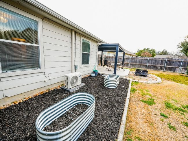 View of yard with ac unit, a fenced backyard, a patio area, and an outdoor fire pit | Image 9