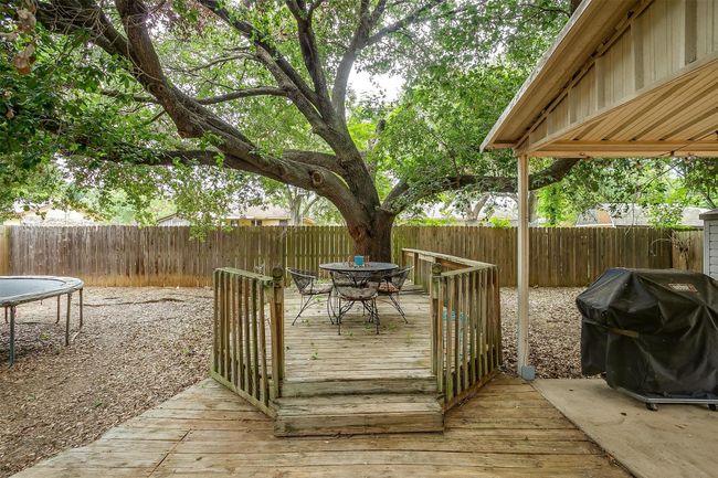 Wooden deck with outdoor dining space, grilling area, and a fenced backyard | Image 35