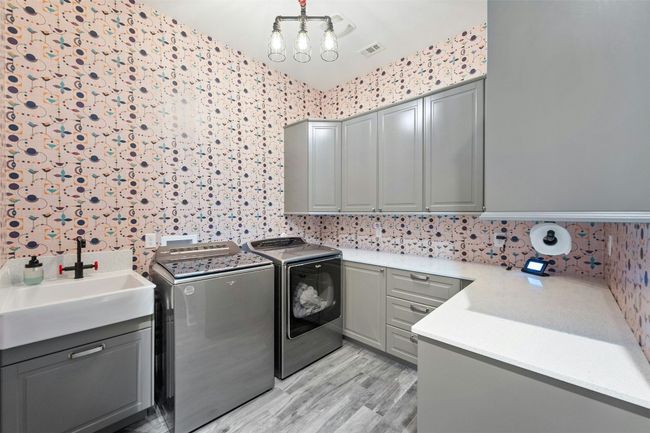 The cheerful wallpaper will make you whistle while you work in your large functional laundry room. | Image 32