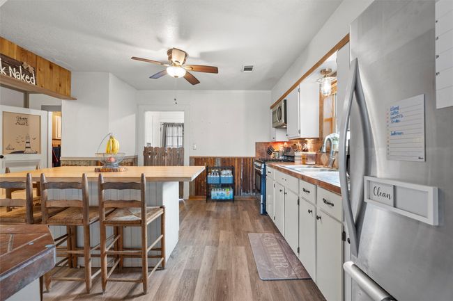 Kitchen with a ceiling fan, stainless steel appliances, a sink, visible vents, and white cabinets | Image 8