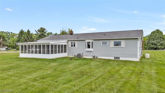 Back of house featuring central air condition unit, a sunroom, a lawn, and a chimney | Image 25