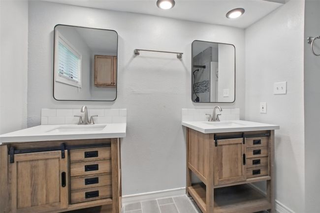 Enjoy modern finishes in the primary bathroom, featuring matching designer mirrors, recessed lighting, and a seamless glass shower (not pictured). | Image 22