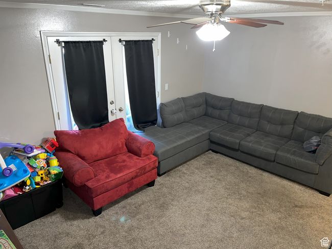 Carpeted living area featuring a textured ceiling, ornamental molding, and ceiling fan | Image 4