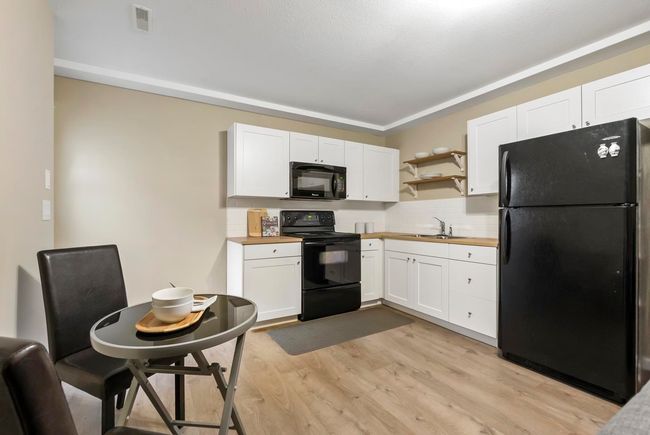 Kitchen featuring black appliances, white cabinetry, visible vents, and wooden counters | Image 26