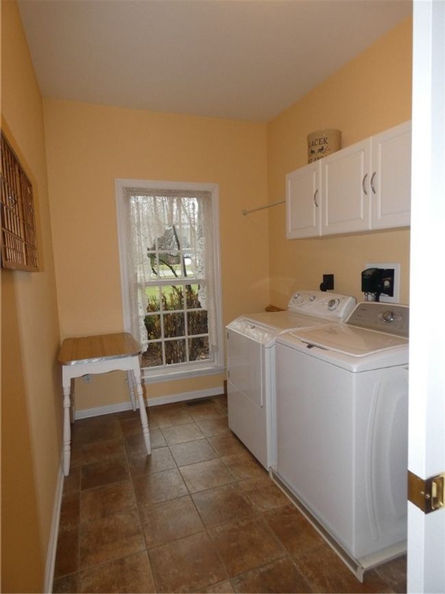 The large first floor laundry w/pocket door offers a folding area and storage cabinetry | Image 26