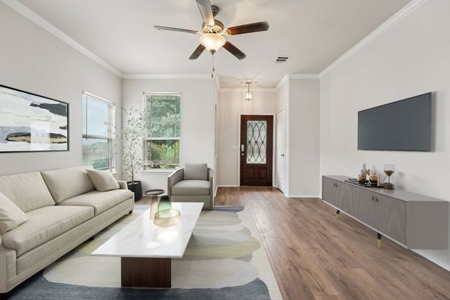 Living room with wood finished floors, a ceiling fan, crown molding, and baseboards | Image 6