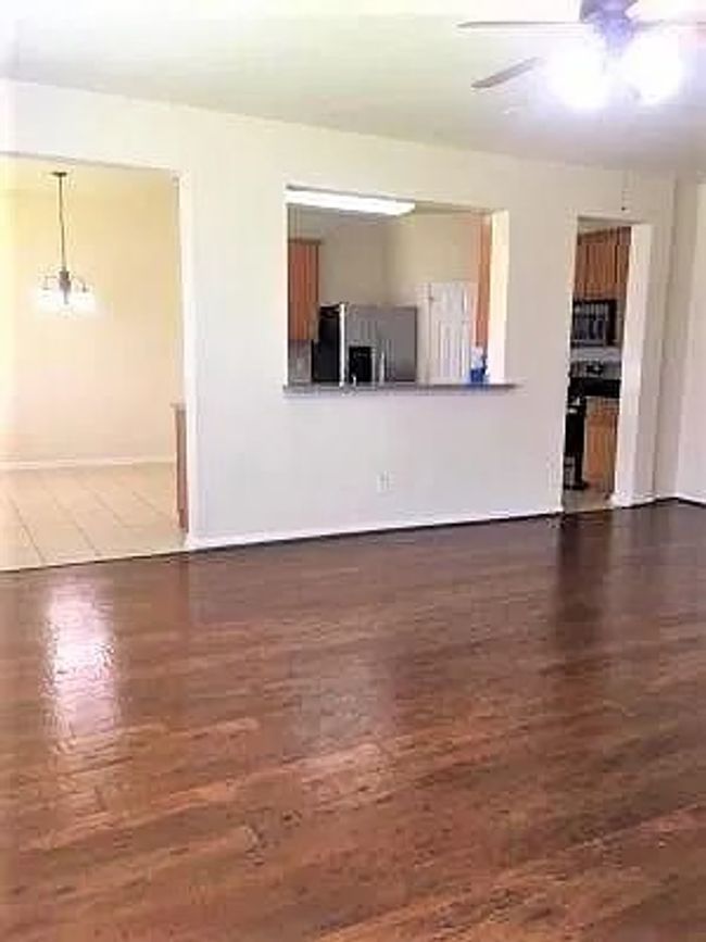 Unfurnished living room featuring ceiling fan, wood finished floors, and baseboards | Image 5