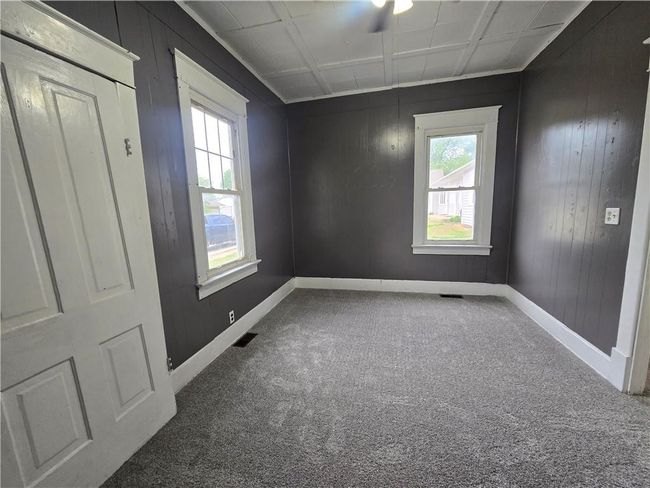 Carpeted empty room with baseboards and wood walls | Image 18
