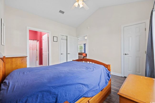 Bedroom featuring dark wood-style floors, lofted ceiling, connected bathroom, a ceiling fan, and baseboards | Image 18