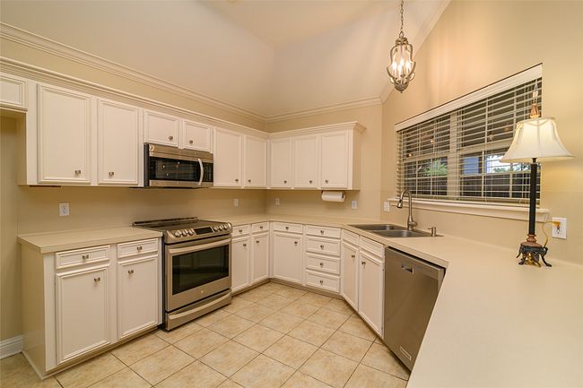 Kitchen featuring appliances with stainless steel finishes, a sink, light tile patterned flooring, light countertops, and white cabinetry | Image 6