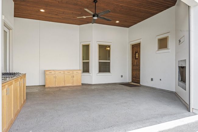 Covered terrace/patio features gas cooktop, sink cabinetry, outdoor fireplace and ceiling fan. | Image 10