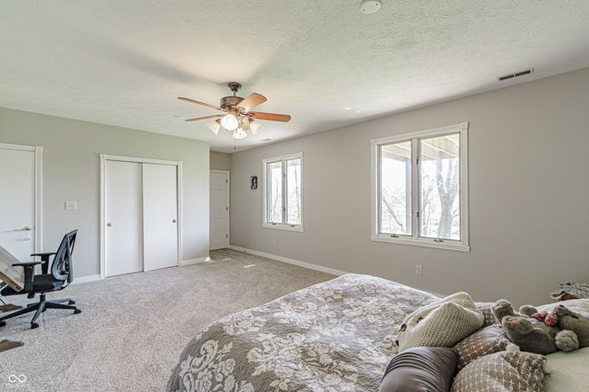 bedroom with a textured ceiling, baseboards, visible vents, carpet, and a ceiling fan | Image 34