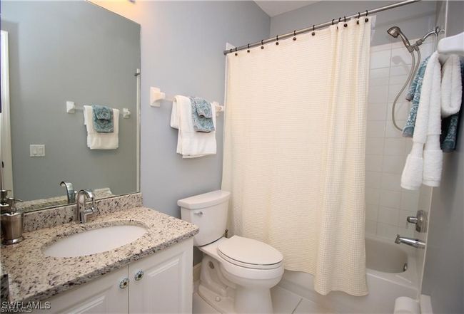 Full bathroom featuring tile patterned flooring, vanity, toilet, and shower / bath combo with shower curtain | Image 14
