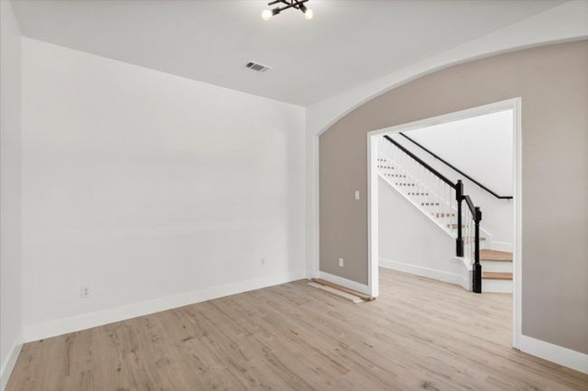 Unfurnished room with light wood-style floors, stairs, and arched walkways | Image 4