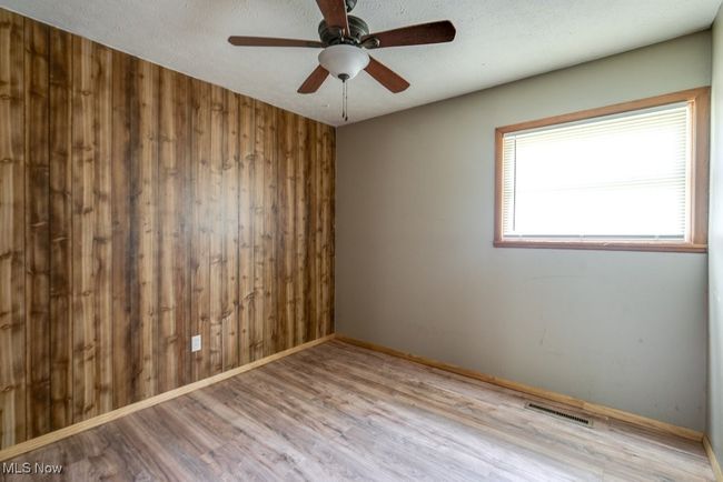 Spare room featuring wooden walls, wood finished floors, baseboards, and a ceiling fan | Image 24