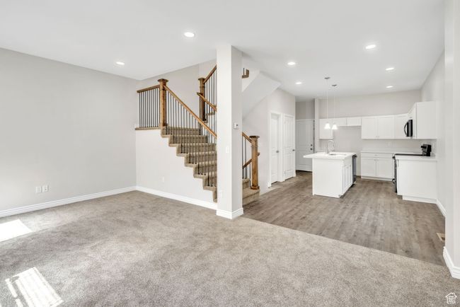Kitchen featuring light carpet, open floor plan, a center island with sink, white cabinets, and recessed lighting | Image 9