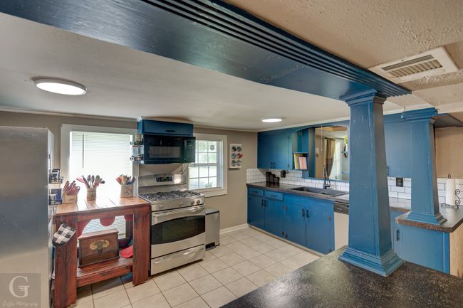 Kitchen featuring blue cabinets, stainless steel appliances, dark countertops, a sink, and a textured ceiling | Image 12
