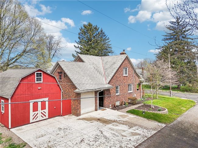 View of front of house featuring a chimney, concrete driveway, an outdoor structure, brick siding, and a barn | Image 32