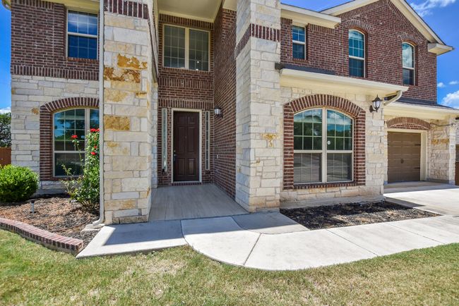 Property entrance with stone siding, a garage, and brick siding | Image 6