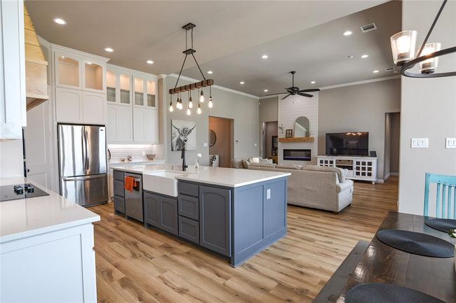 Kitchen with light wood-style floors, a fireplace, backsplash, white cabinetry, and appliances with stainless steel finishes | Image 10