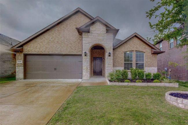 French country style house with a front lawn, driveway, stone siding, and a garage | Image 4