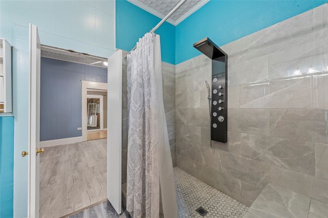 Bathroom with crown molding, a tile shower, and wood finished floors | Image 12