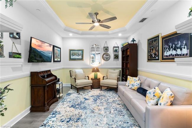 Living area with wood finished floors, ornamental molding, a tray ceiling, a ceiling fan, and recessed lighting | Image 15